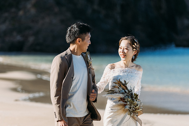 静岡の海辺で笑顔で向き合う夫婦のウェディングフォト