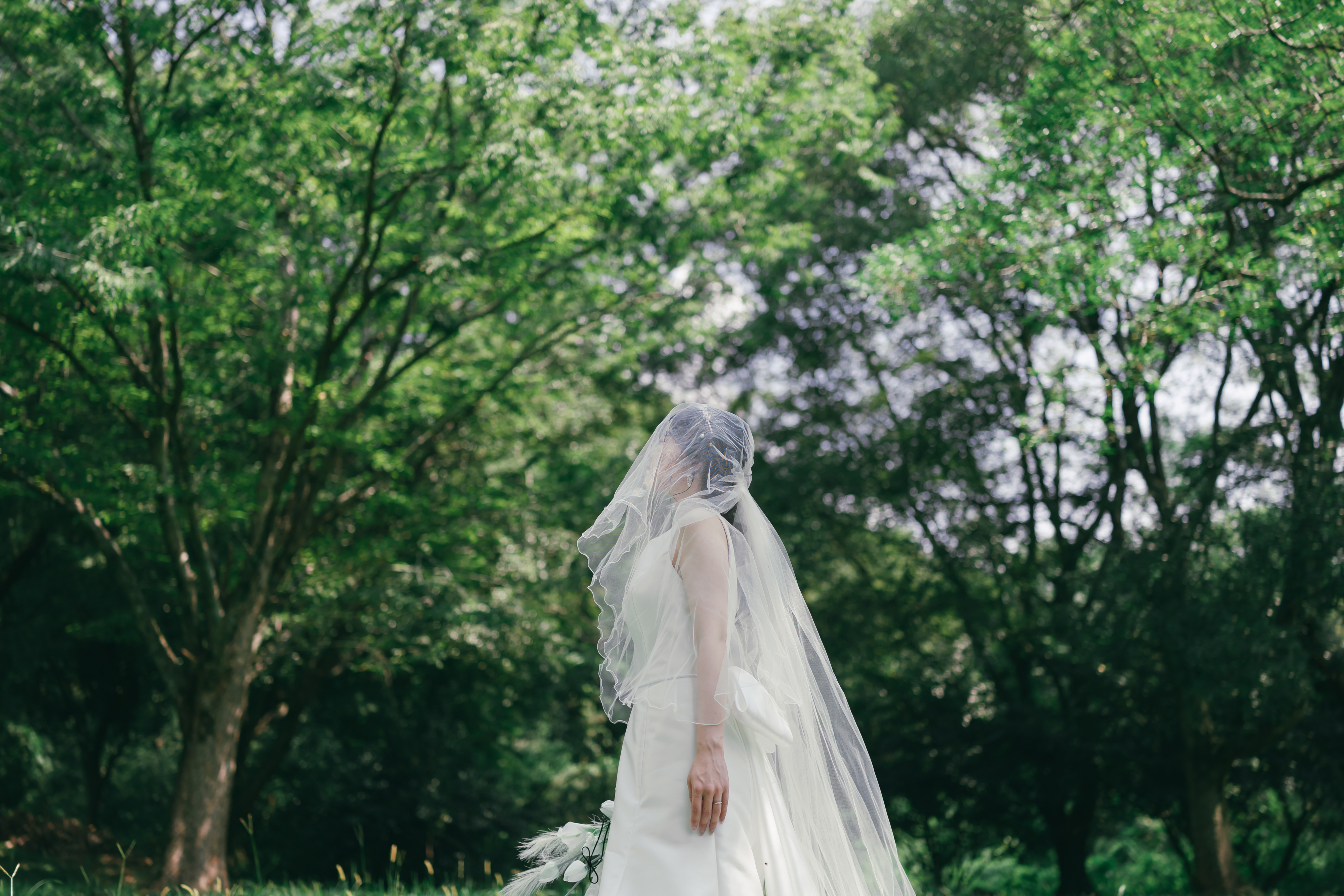 木陰で空を見上げる新婦のウェディングフォト