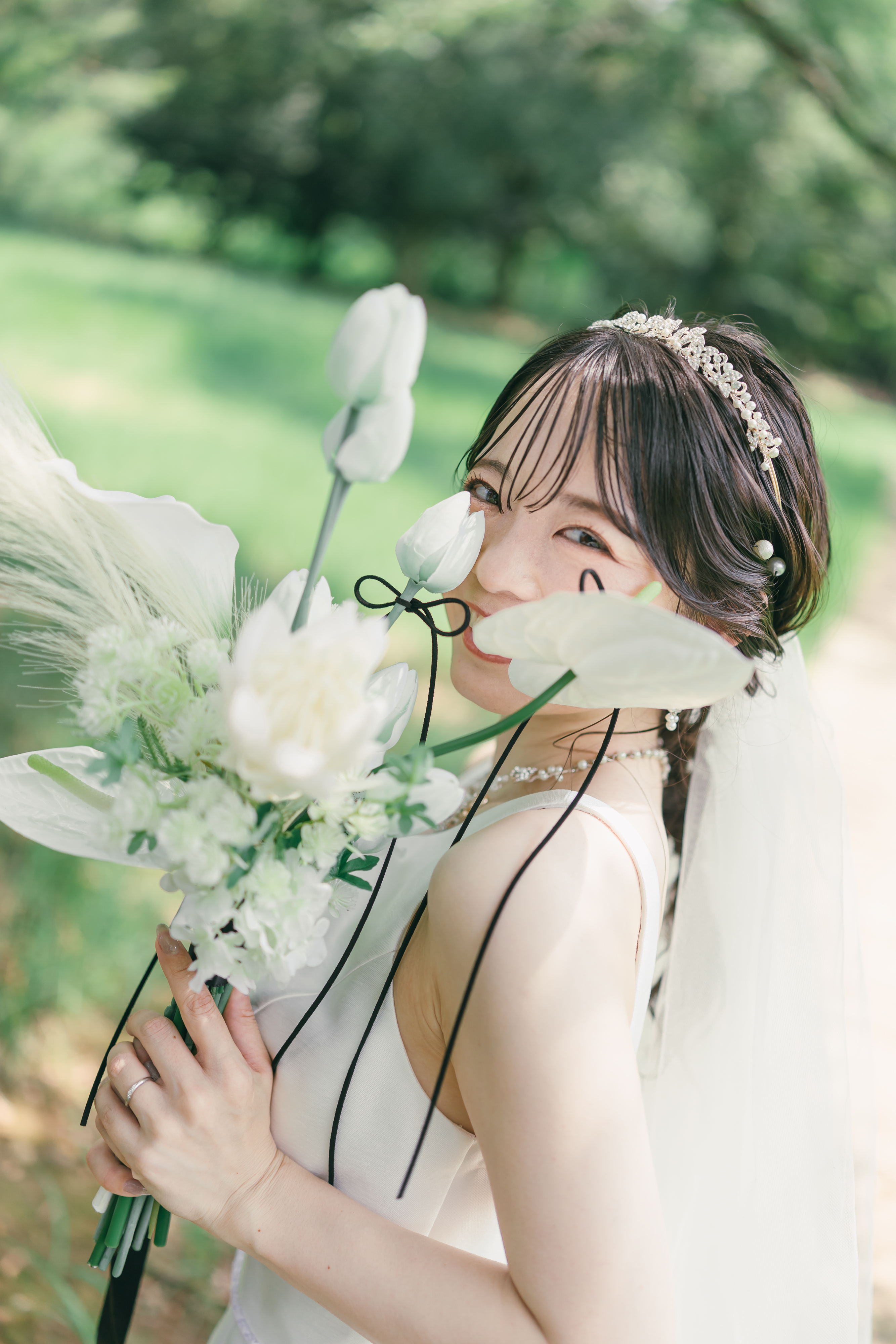 花を持ち笑顔を見せる新婦のウェディングフォト